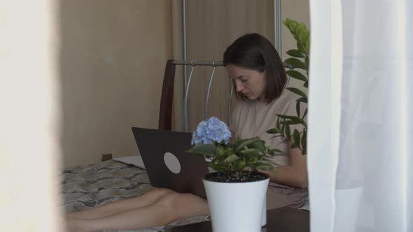 Woman with Laptop in Room with Flowers
