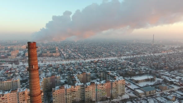 Aerial Shot of an Incredibly High Tower with Slow Smoke at Sunset in Winter