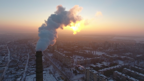 Aerial Shot of a Sky High Chimney with Slow White Smoke at Sunset in Winter