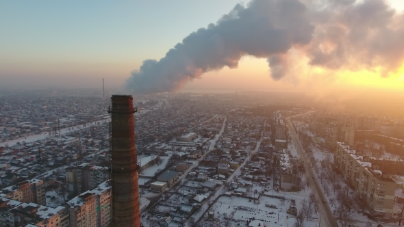 Aerial Shot of a Giant Chimney with Slow White Smoke at Sunset in Winter