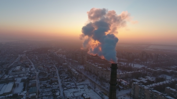Aerial Shot of a Colossal Industrial Tower with Thick Smoke at Sunset in Winter