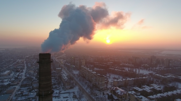 Aerial Shot of an Elevated Industrial Tower with Heavy Smoke at Sunset in Winter