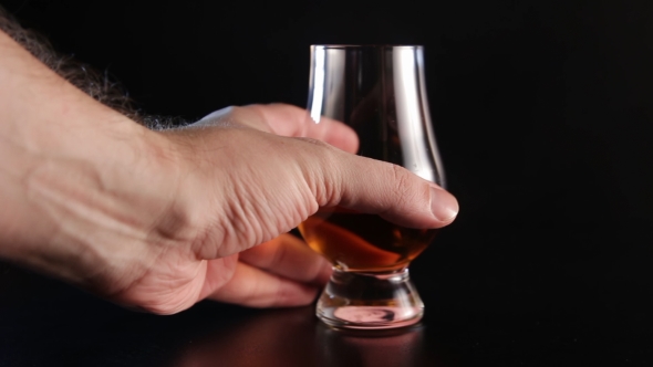 A Hand Picks Up a Glass Alcohol Drink and Than Puts It Back