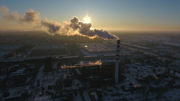 Aerial Shot of a Soaring Brick Tower with White Smoke at a Nice Sunset in Winter