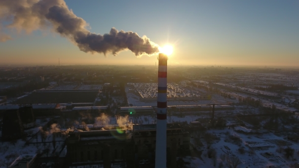 Aerial Shot of a White and Red  Chimney with White Smoke at Sunset in Winter