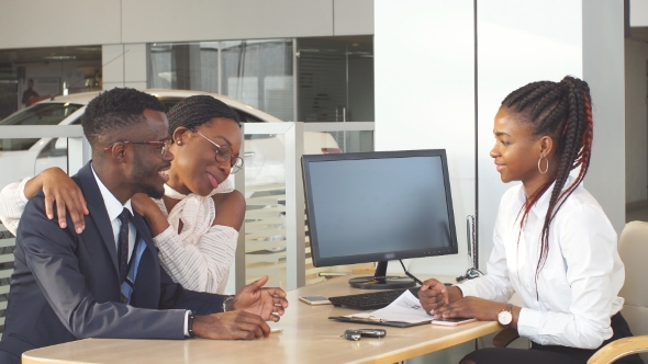 Happy Couple with Salesman Signing Contract and Taking Key To New Car. alt