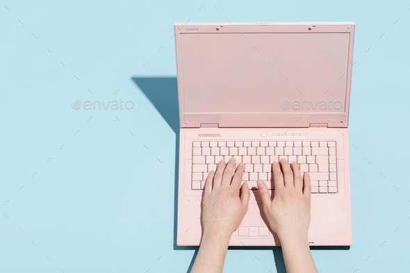 Woman\'s hands typing on a pastel pink keyboard