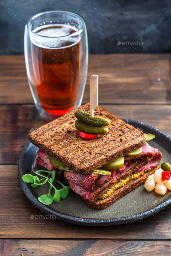 Delicious huge pastrami sandwich with beer and pickle Stock Photo by