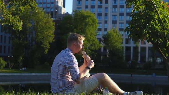 stylish man eating shawarma in city park