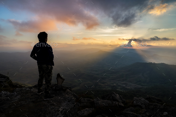 Young man hiker relaxing on top of a mountain at sunset - Stock Photo - Images