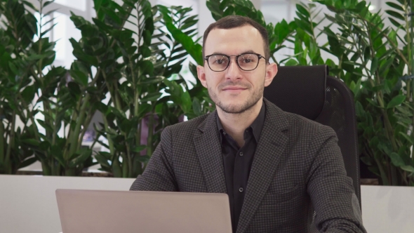 Handsome Business Man Using a Laptop Looking at the Camera and Smiling alt