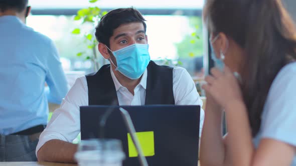 business meeting Freelance caucasian male and asian female putting protective face mask alt