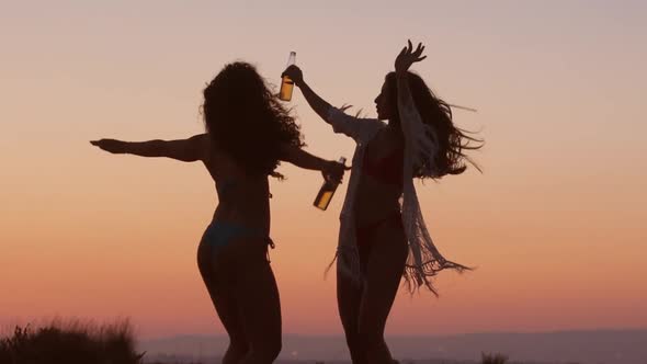Women Dancing and Drinking Beer at Beach Party at Sunset