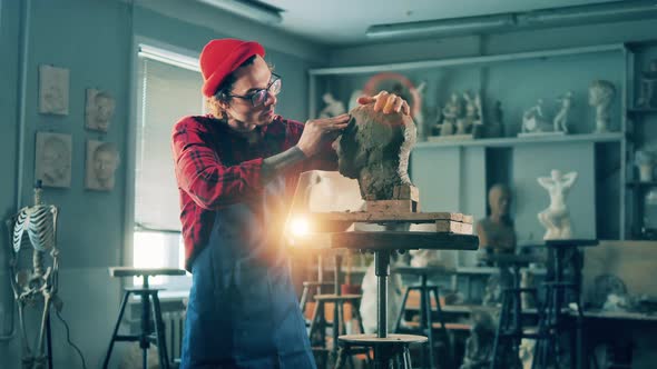 Male Artist is Working with a Clay Sculpture in the Studio alt