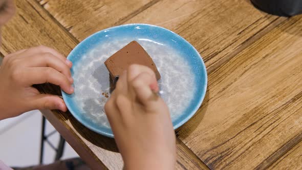 Little Girl Eats Tasty Chocolate Brownie at Cafe alt