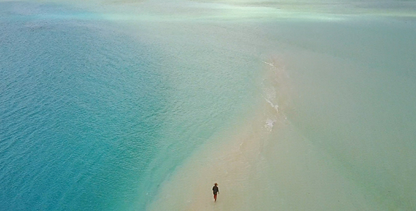 Aerial of Girl Walking Along Sandbank in the Maldives Surrounded by Blue Ocean