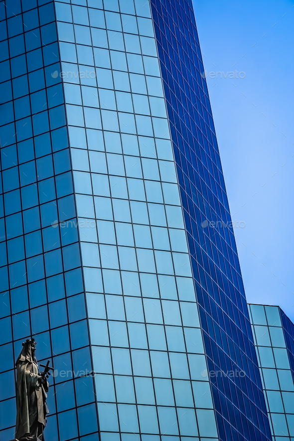 Statue of holy Mary in front of modern glass office building in - Stock Photo - Images