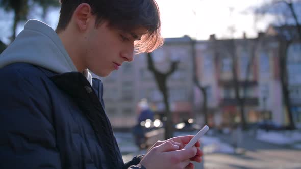 Young Man Texting on Cell Phone Looking Around alt