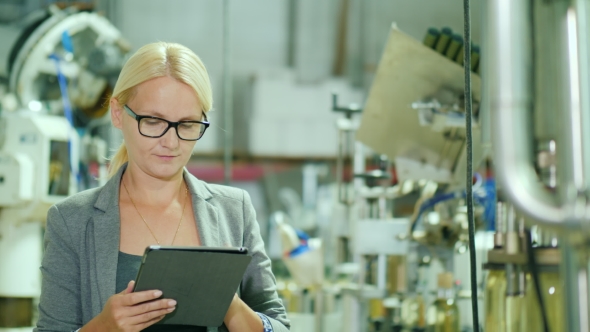 A Woman in a Suit Works with the Tablet in a Room for Wine Production Plant alt