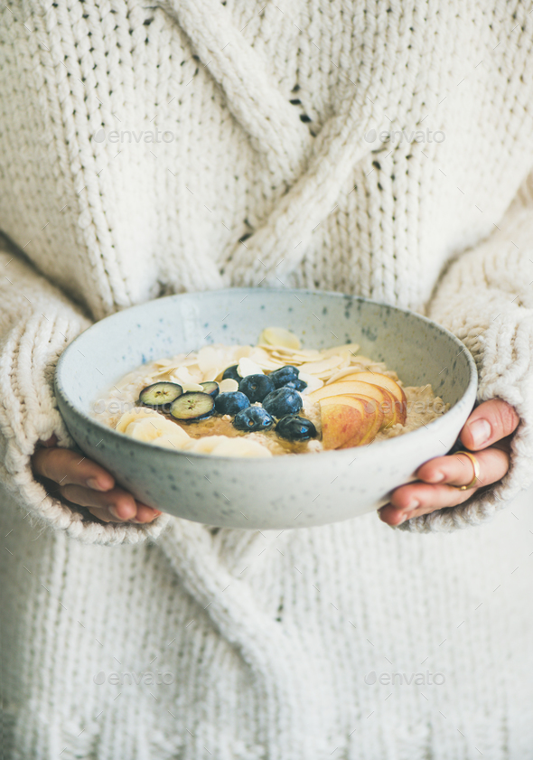 Woman in sweater holding bowl of oatmeal porriage - Stock Photo - Images