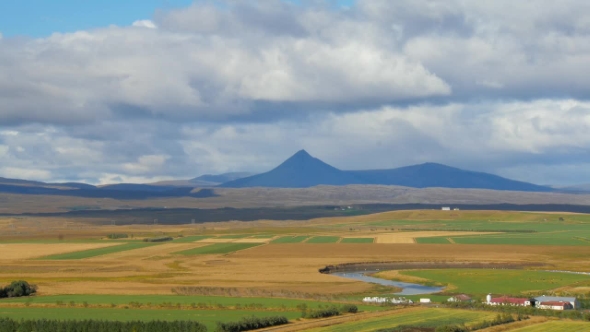Agricultural Fields, Meandering River and Dark High Mountain in Icelandic Landscape
