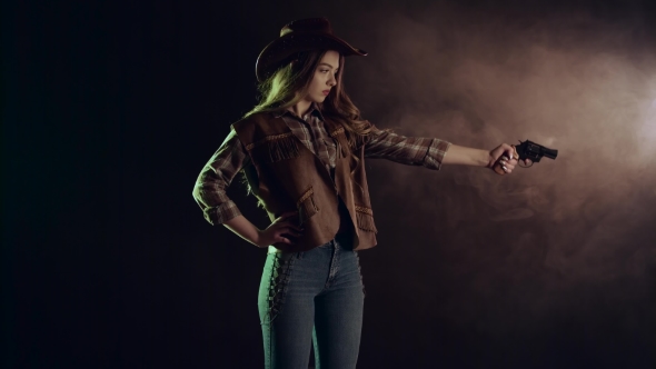 Sheriff Girl Holds a Revolver in Her Hands and Aiming at the Villain. Black Smoke Background. . Side alt