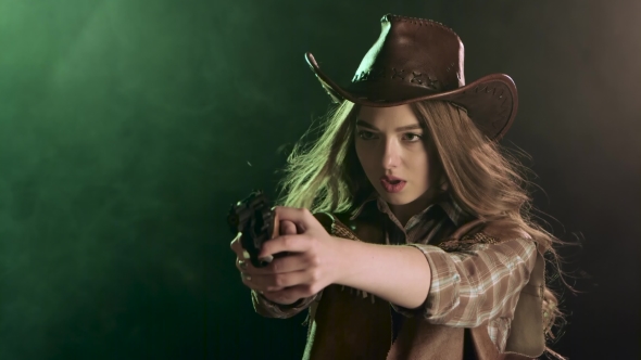 Cowgirl Holds a Revolver in Her Hands and Aiming at the Villain. Black Smoke Background. alt