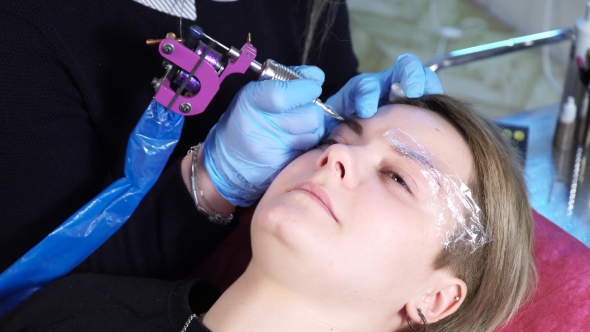 Beautician, Specialist of Permanent Make-up Is Applying Local Anesthetic Before the Eyebrows