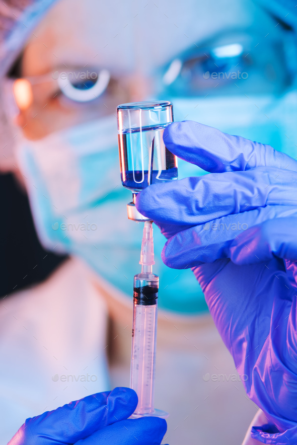 Doctor drawing up solution and filling syringe - Stock Photo - Images