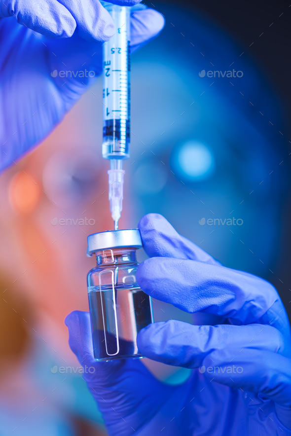 Doctor drawing up solution and filling syringe - Stock Photo - Images