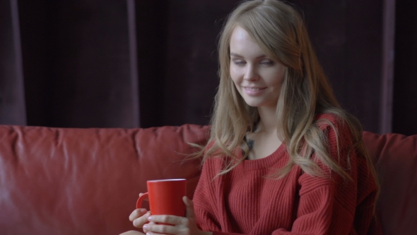Cute Young Smiling Girl in Red Sweater Enjoying Her Coffee at Home