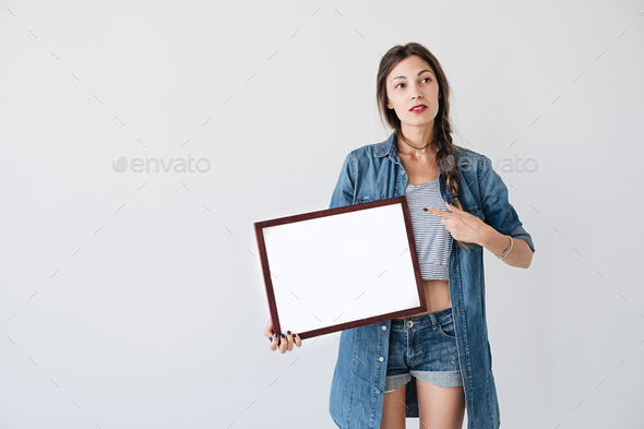 Girl showing to an empty frame - Stock Photo - Images