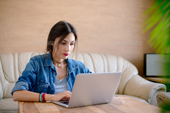 Serious young woman working on a laptop in office - Stock Photo - Images