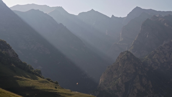 Strips of Light Rays in the Mountains and a Lone Paraglider