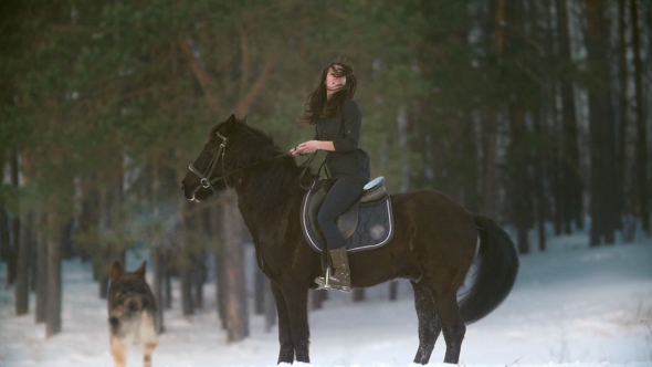 Professional Beautiful Longhaired Woman Riding a Black Horse Through the Deep Snow in the Forest alt