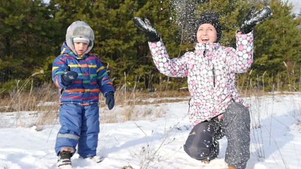 Happy Woman and Child Playing with Snow in the Winter Forest, in a