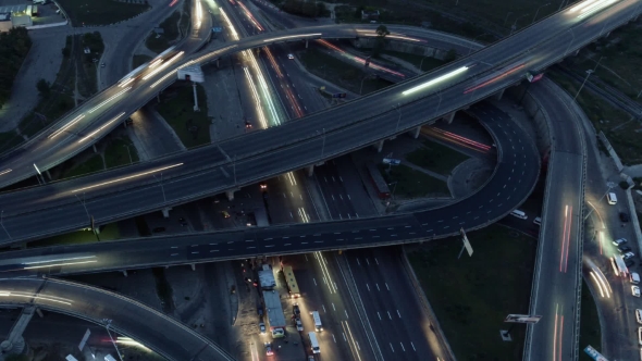 Overhead Flyover the Complex Road Junction Highway. Night Light, Sunset. High Altitude Drone Flight.