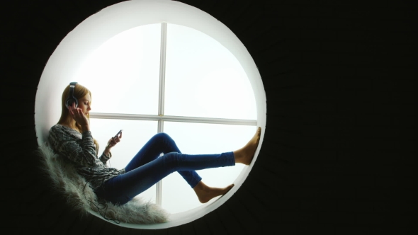 Attractive Woman Sitting at the Round Window, Listening To Music alt