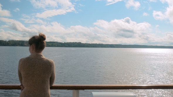 Young Woman Standing on Deck of Cruise Ship and Looking at River and Landscape