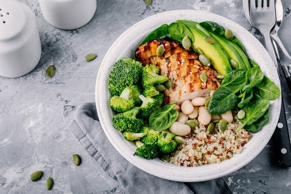 Green buddha bowl lunch with grilled chicken and quinoa, spinach, avocado, broccoli and white beans Stock Photo by nblxer