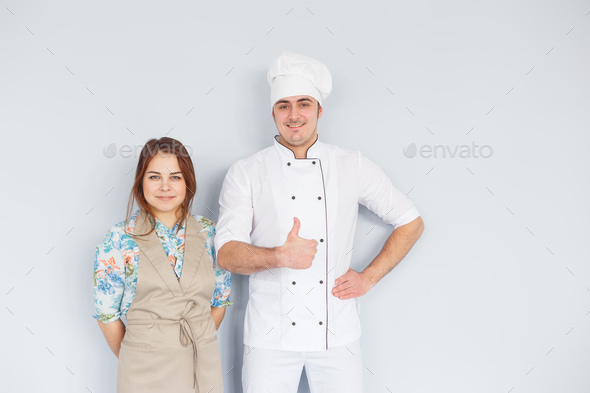 Chef men and woman wearing apron isolated on light background. Couple at work. Thumb up Stock Photo by Vladdeep