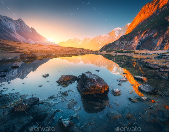 Mountains with illuminated peaks, stones in mountain lake at sunset - Stock Photo - Images