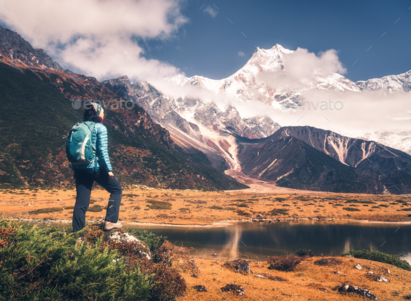 Standing young woman with backpack and mountains - Stock Photo - Images
