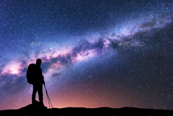 Man with backpack and trekking poles and Milky Way Stock Photo by den-belitsky