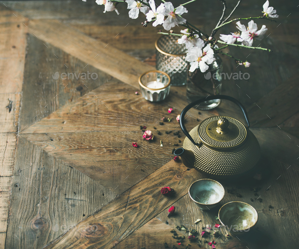 Asian golden iron teapot, cups, candles and almond blossom flowers - Stock Photo - Images