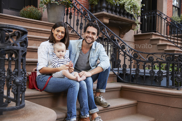 Young family with kids sitting on front stoops Stock Photo by monkeybusiness