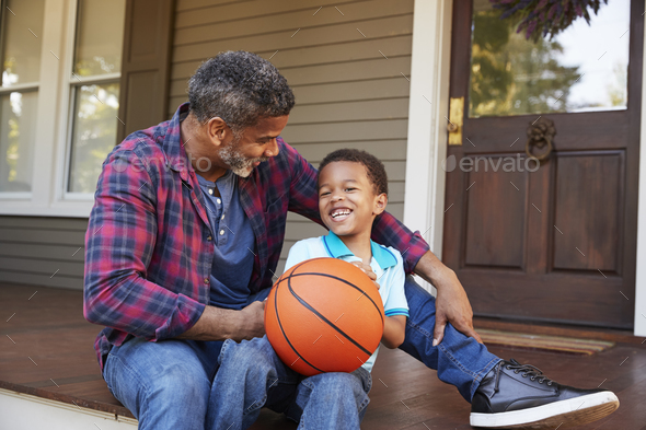 Father And Son Discussing Basketball On Porch Of Home Stock Photo by monkeybusiness