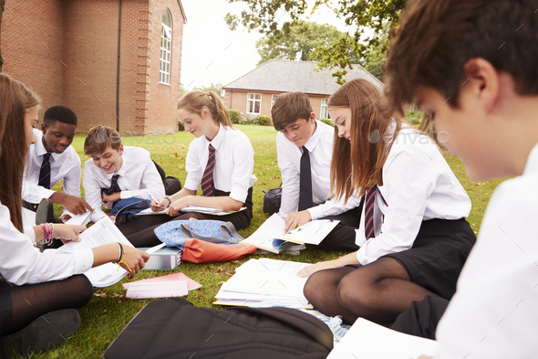 Teenage Students In Uniform Working On Project Outdoors Stock Photo by monkeybusiness