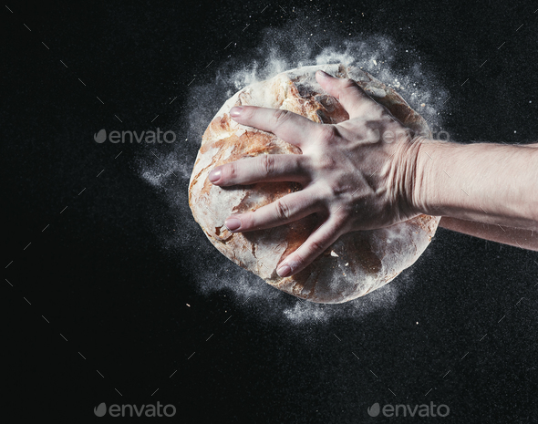 Closeup of male hands put fresh bread on black background with copy space for your text - Stock Photo - Images