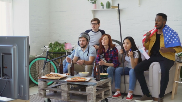 Multi Ethnic Group of Friends with USA National Flags Watching Sport Championship on TV Together and alt